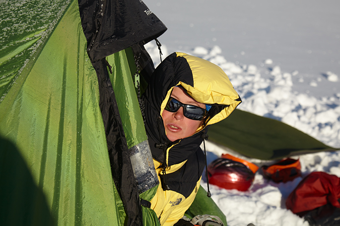 горный турист вылезает из палатки