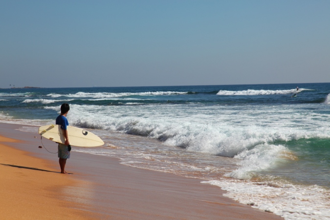Человек с серфом на пляже в Хиккадуве, Шри Ланка