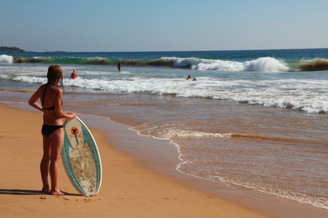Девушка с серфом на пляже в Хиккадуве, Шри Ланка