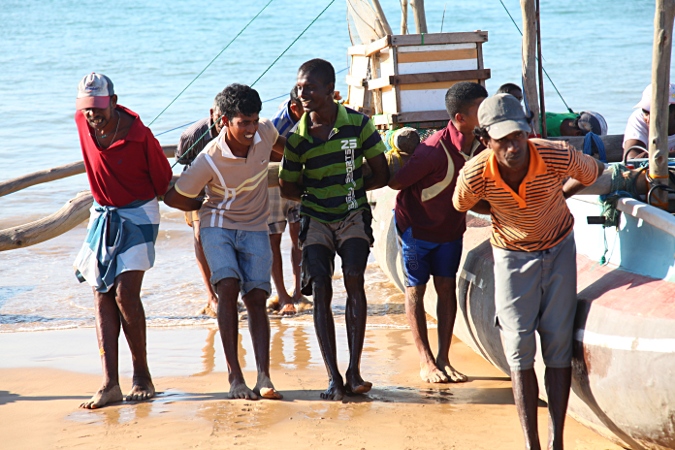 Рыбаки спускают лодку на воду на Шри Ланке
