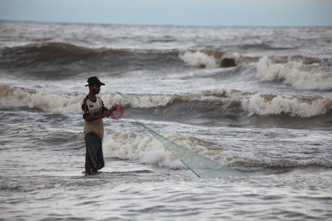 рыбак вытягивает сеть из океана на Шри-Ланке